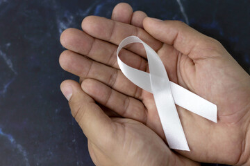 White January, mental health awareness campaign. Man holding a white ribbon. - obrazy, fototapety, plakaty