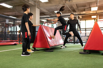 Active children having exercise class with their coach in gym