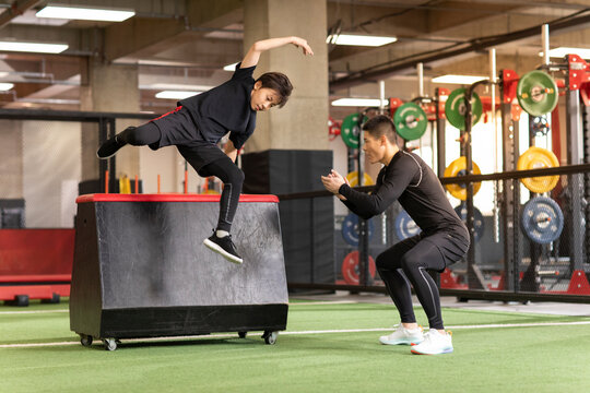 Little boy having exercise class with coach in gym