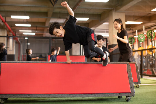 Active children having exercise class with their coach in gym