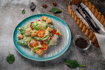 Healthy salad with fried shrimp, greens and croutons in a plate against a gray stone table. A healthy breakfast in a restaurant