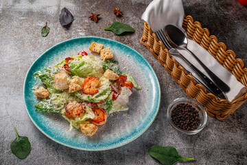 Healthy salad with fried shrimp, greens and croutons in a plate against a gray stone table. A healthy breakfast in a restaurant