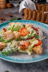 Healthy salad with fried shrimp, greens and croutons in a plate against a gray stone table. A healthy breakfast in a restaurant