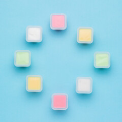 A set of multicolored yogurt cups on a blue background. Natural healthy food. Flat lay.