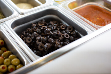 A view of an ingredient station display, featuring sliced black olives.