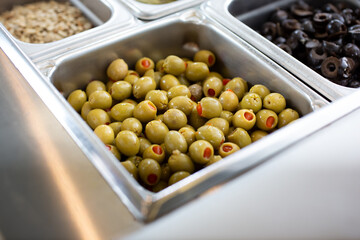 A closeup view of green pimiento olives in a steamer food pan, in a restaurant setting.