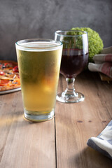 A view of a beer glass and wine glass next to a pizza.