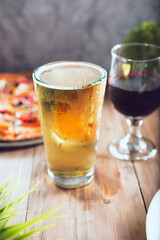 A view of a beer glass and wine glass next to a pizza.