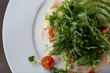 A top down view of an egg white omelet, with an arugula salad.