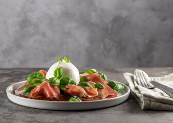 Delicious Italian appetizer. Buffalo burrata cheese served with fresh tomatoes, prosciutto, and basil leaves. copy space.