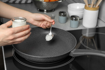 Woman cooking with coconut oil on induction stove, closeup