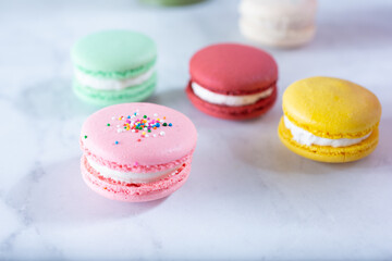 A view of several macaron cookies on a marble surface.