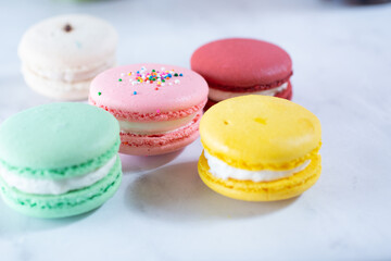 A view of several macaron cookies on a marble surface.