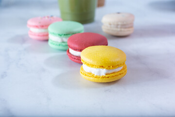 A view of several macaron cookies on a marble surface.