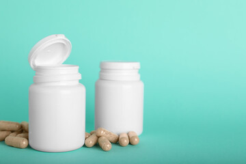 Gelatin capsules and bottles on turquoise background, space for text
