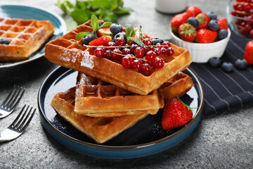 Delicious Belgian waffles with berries served on grey table