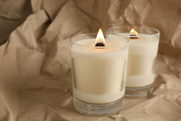 Burning soy candles with wooden wicks on crumpled kraft paper