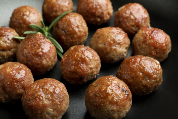 Tasty cooked meatballs and rosemary in frying pan, closeup