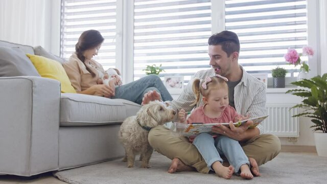Happy young family with newborn baby and little girl enjoying time together at home.