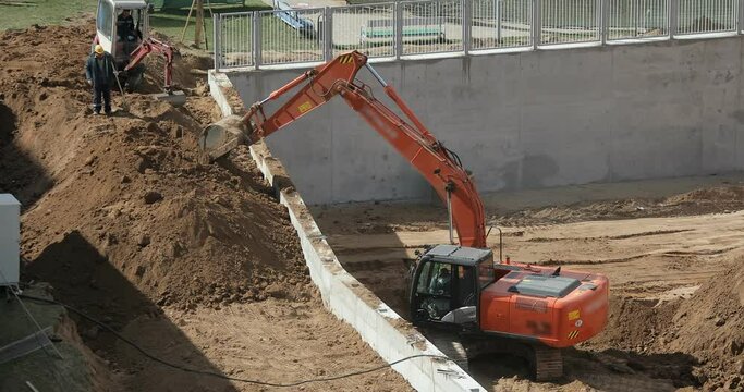 Excavator loading sand at a construction site. Construction of a kindergarten in the city.