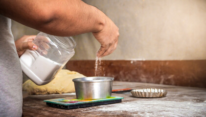Baker pours sugar into a bowl. baker preparing ingredients to prepare a rich artisan bread. Small business concept