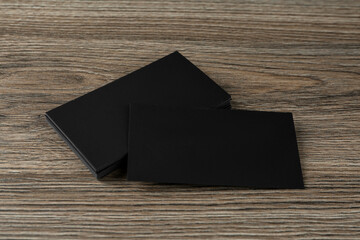 Blank black business cards on wooden background. Mockup for design