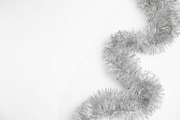 Silver tinsel on white background, top view. Space for text