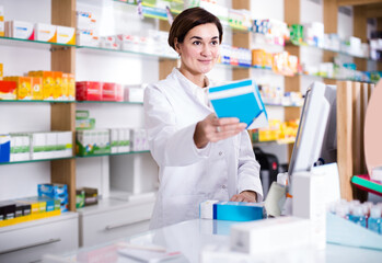 Smiling spanish female pharmacist offering assistance at counter in pharmacy