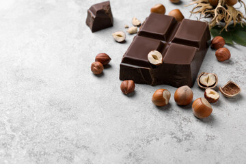 Delicious chocolate and hazelnuts on light table, space for text