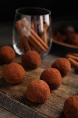 Delicious chocolate truffles powdered with cocoa on wooden board, closeup