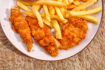 Tasty french fries with deep fried chicken wings on plate, closeup