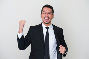 Adult Asian man wearing black suit and tie clenched fist showing winning gesture
