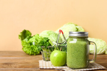 Mason jar of healthy green smoothie, apple and vegetables on wooden background