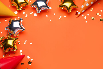 Beautiful balloons, party hats and confetti on orange background