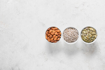 Bowls with sunflower, pumpkin seeds and almond nuts on grunge background