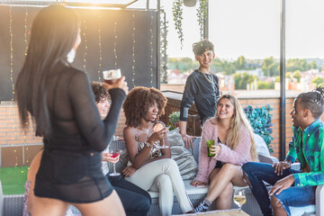 Happy multiethnic friends on a terrace having fun and drinking