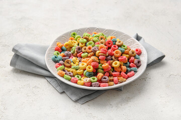Plate of colorful cereal rings on light grunge background