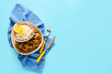 Plate with tasty beef curry and rice on blue background