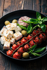 feta cheese and baked cherry tomatoes, basil and olives, salad, selective focus