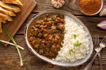Plate with tasty beef curry and rice on wooden background