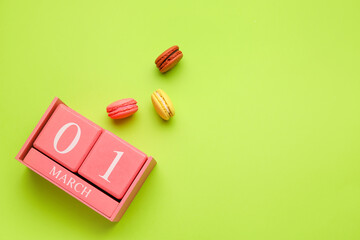 Calendar with date of International Women's Day and cookies on green background