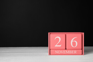 Calendar with date of Black Friday on table against dark background