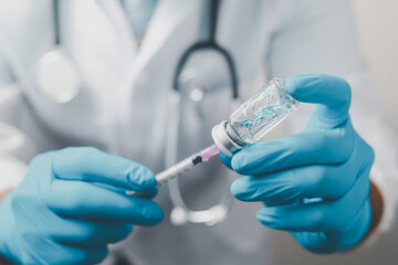 A doctor or scientist in the COVID-19 medical vaccine research and development laboratory holds a syringe with a liquid vaccine to study and analyze antibody samples for the patient.
