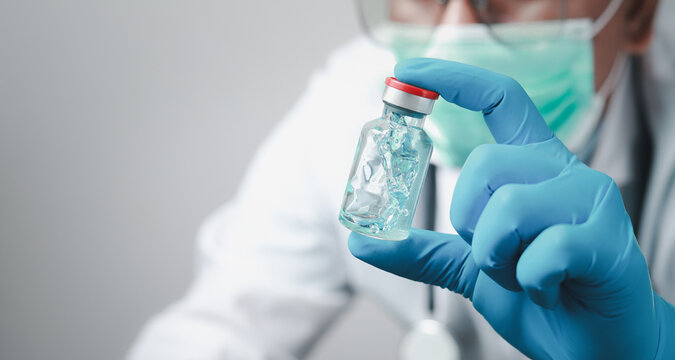 A doctor or scientist in the COVID-19 medical vaccine research and development laboratory holds a syringe with a liquid vaccine to study and analyze antibody samples for the patient.
