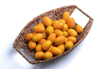 Orange Kumquat in a wicker basket on a white background.