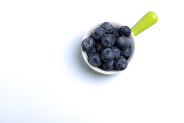 Blueberries in a ceramic cup on a white background.