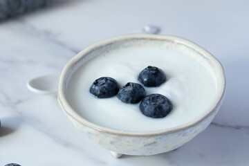 fresh blueberry yogurt in white cup on marble background