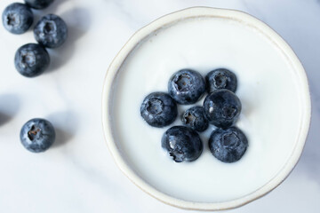 fresh blueberry yogurt in white cup on marble background