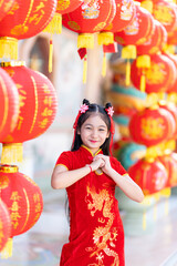 little Cute Asian girl wearing traditional Chinese cheongsam red with paper lanterns with the...