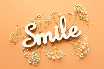 Word SMILE with beautiful gypsophila flowers on orange background